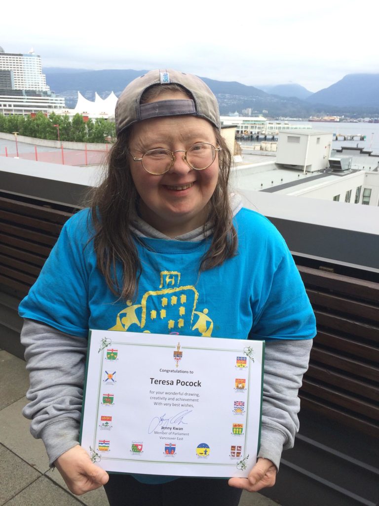 Teresa Heartchild holding the achievement certificate awarded to her by MP Jenny Kwan